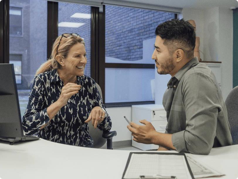 Two colleagues talking at a desk in an office